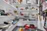 Storage area featuring white tiered shelving and a wall-mounted pegboard system
