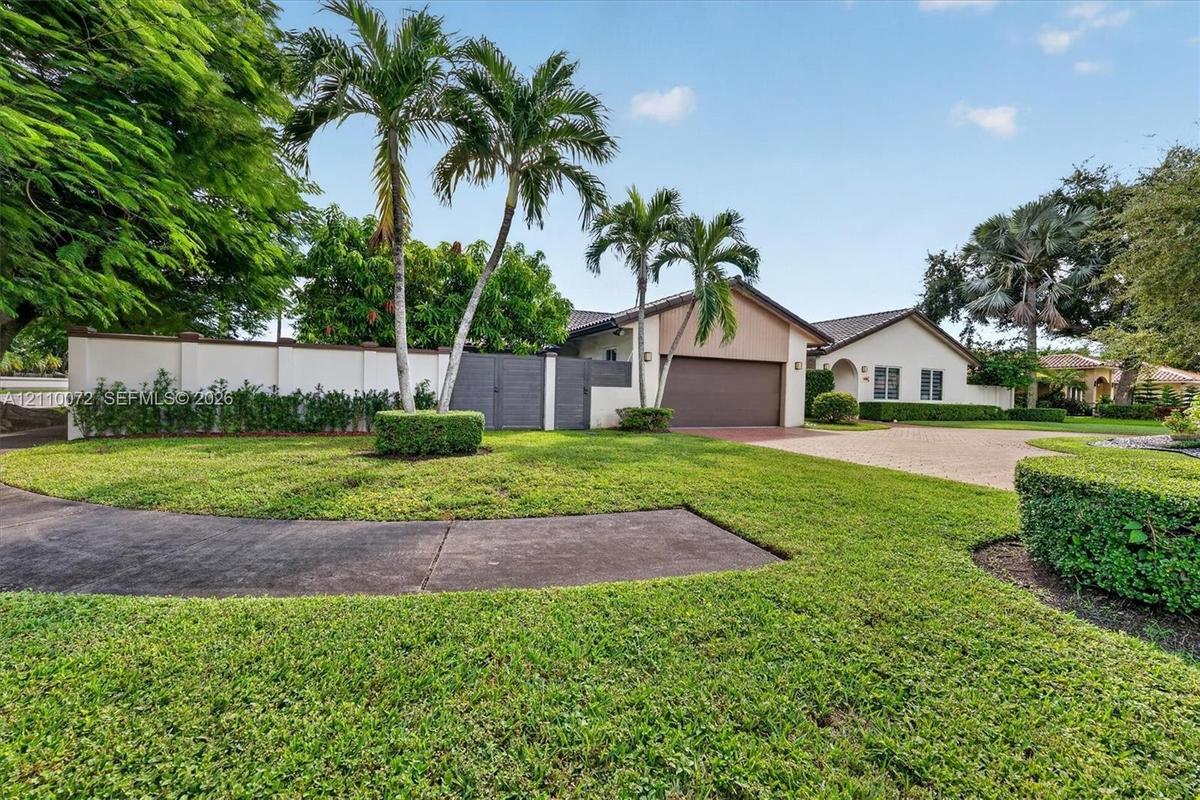 Single-story exterior featuring a paver driveway, an attached garage, and a solid perimeter privacy wall with gated entry