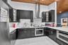Kitchen featuring dark cabinetry, white stone countertops, stainless steel appliances, a stainless steel range hood, and a wood-plank ceiling