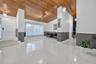 Vaulted wood-plank ceiling, large-format tile flooring, dual-tone wall finishes, and recessed and pendant lighting fixtures