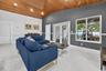 Vaulted ceiling with wood-plank finish, recessed lighting, large-format tile flooring, and dual glass-panel patio doors