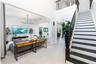 Two-story foyer with high ceilings, large-format tile flooring, a geometric multi-arm chandelier, and a staircase featuring black-painted treads and a