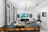 Living area featuring high ceilings, arched windows with plantation shutters, tile flooring, and a modern multi-arm chandelier