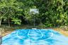 Outdoor basketball court featuring a vibrant blue surface, integrated court markings, and a transparent backboard