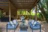 Covered outdoor patio featuring wood-paneled walls, a built-in bar, stone-paver flooring, and an attached ceiling fan