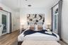 Wood-finish flooring, high ceilings, arch-top window with plantation shutters, and a glass-paneled exterior door