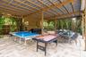 Covered outdoor patio featuring a structural wood frame, stone-tile flooring, built-in bar, and mounted ceiling fans