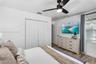 Room featuring wood-finish flooring, a ceiling fan with integrated lighting, dual-panel closet doors, and multi-pane window with horizontal blinds
