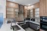 Kitchen featuring custom wood-finish cabinetry, stone-surface countertops, a herringbone-patterned tile backsplash, a stainless steel range hood, and 