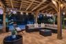 Covered timber-frame pergola featuring exposed rafters, stone-paver flooring, a ceiling-mounted fan, and string lighting