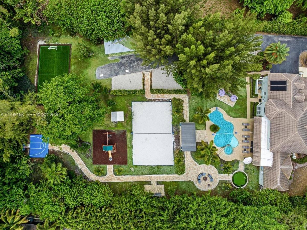 Expansive grounds featuring a swimming pool with integrated spa, multi-sport court, dedicated pickleball court, turf soccer area, and stone-paver walk