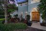 Stucco exterior featuring double arched wood front doors with decorative iron detailing, classical architectural columns, arched windows, and a paved 