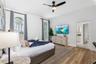 Wood-finish flooring, high ceilings with a central fan, and arched windows featuring custom shutters