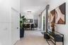 Large-format neutral floor tile, multi-light pendant chandelier, and sliding glass door with ceiling-mounted drapery hardware