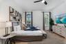 Arched windows with shutters, wood-finish flooring, and a ceiling fan with integrated lighting