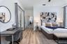 Bedroom featuring wood-finish flooring, high ceilings, ceiling fan, and double glass-paneled doors with shutter-style treatments