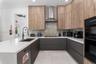 Kitchen featuring dual-tone cabinetry with wood-finish uppers, quartz countertops, herringbone-patterned tile backsplash, stainless steel range hood, 