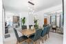 Open-concept interior featuring oversized light-toned floor tiling, a multi-light contemporary pendant fixture, and a minimalist kitchen island with c