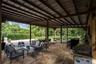 Covered outdoor patio featuring stone-tiled flooring, a stained-wood beam ceiling, and an integrated grilling station