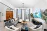Living area featuring high ceilings, arched windows with plantation shutters, a multi-arm chandelier, and double wood entry doors with an arched trans
