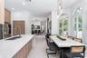 Kitchen featuring a large quartz-topped center island with integrated sink, wood-finish cabinetry, recessed lighting, and expansive arched windows wit