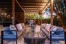 Covered outdoor patio featuring paver flooring, wood-beam ceiling construction, wall-mounted fan, integrated lighting, and a built-in outdoor cooking 