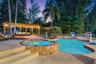 Outdoor space featuring a swimming pool, an integrated spa with stone masonry, a wood-frame pergola, and concrete decking
