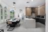Kitchen featuring two-tone flat-panel cabinetry, a waterfall-edge center island, stainless steel range hood, herringbone tile backsplash, and arched w