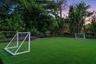 Expansive lawn featuring artificial turf, mature tree border, and perimeter landscaping