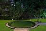 Backyard putting green featuring three flag pins, synthetic turf surface, stone border edging, and stone paver walkway