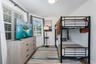 Room featuring wood-finish flooring, multiple windows with horizontal blinds, and a flush-mount overhead light fixture