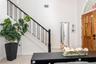Entryway featuring double-height ceilings, a staircase with black metal balusters, and a wood-paneled door with an arched transom window