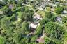 Aerial perspective of a multi-story residence featuring an in-ground swimming pool, a hardscaped sport court, extensive mature landscaping, and solar 