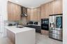 Kitchen featuring wood-finish cabinetry, stone-surface countertops, a herringbone tile backsplash, stainless steel appliances, and a built-in oven