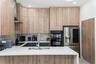 Kitchen featuring wood-finish cabinetry, white solid-surface countertops, a herringbone-patterned tile backsplash, a stainless steel undermount sink w