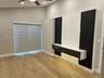 Vaulted ceiling featuring a ceiling fan, wood-finish flooring, and a custom built-in media console with black vertical accent paneling and integrated 