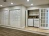 Laundry area featuring built-in cabinetry, recessed lighting, and louvered closet doors, set on a raised tile platform with wood-finish flooring in th