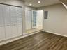 Wood-finish flooring, white louvered closet doors, recessed lighting, and a multi-pane glass door