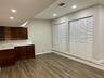 Wood-finish flooring, dark wood cabinetry with stone-patterned countertops, and dual white louvered-style closet doors