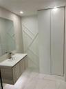 Floating vanity with wood-finish cabinetry, white countertop, integrated sink, and matte metallic faucet, complemented by full-height floor-to-ceiling