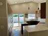 Kitchen featuring flat-panel cabinetry, stone-finish countertops, stainless steel appliances, vaulted ceilings, and pendant lighting