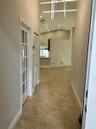 Entryway featuring tile flooring, vaulted ceilings, a stacked stone accent wall, recessed lighting, and a linear modern chandelier