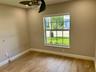 Neutral interior space featuring wood-finish flooring, a multi-pane window with a muntin grid, and an attached ceiling fan with integrated lighting