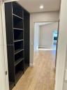 Built-in dark wood-finish cabinetry, light-toned wood-finish flooring, and walls featuring decorative geometric millwork