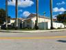 Stucco exterior featuring a tiled roof, concrete driveway, and white vinyl perimeter fencing