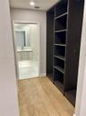 Custom dark-finish built-in shelving, wood-finish flooring, floating vanity with a rectangular sink, wall-mounted faucet, and polished large-format ti