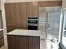 Kitchen featuring floor-to-ceiling wood-finish cabinetry, a built-in stainless steel refrigerator, a wall-mounted microwave and oven combination, and 