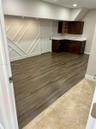 Geometric wall molding, wood-finish flooring, dark-stained cabinetry, light-toned stone-finish countertops, and recessed lighting