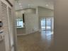 Vaulted ceilings featuring recessed lighting, a stone-finish accent wall, and large-format tile flooring, complemented by sliding glass doors leading 