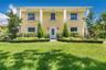 Two-story colonial exterior featuring a covered front porch, prominent structural columns, multi-pane windows with louvered shutters, and window box p